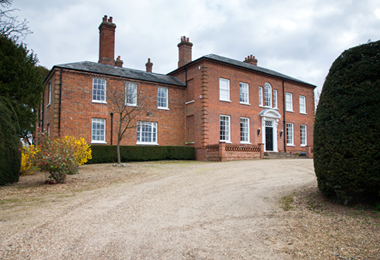 Stately home front view with driveway and bush