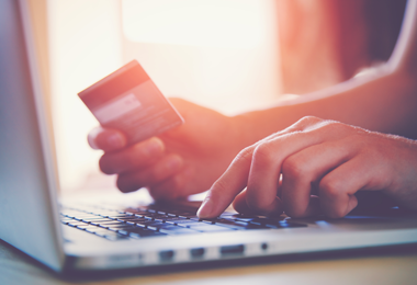 Person typing details into a computer from a credit card