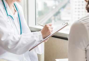 Doctor in white coat and clipboard taking notes in clinic